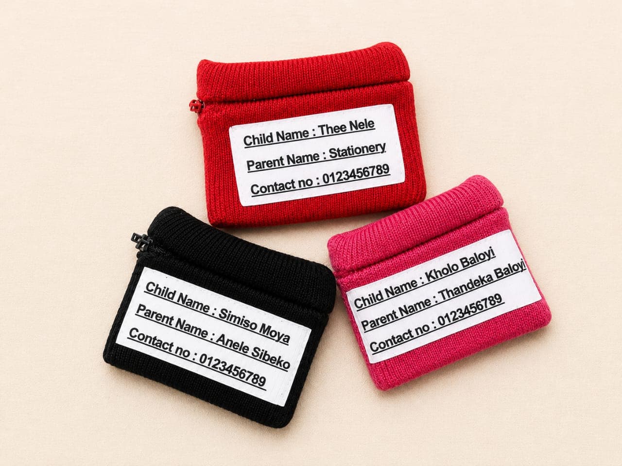 Three personalised wristband wallets with printed ID labels — red, black and pink
